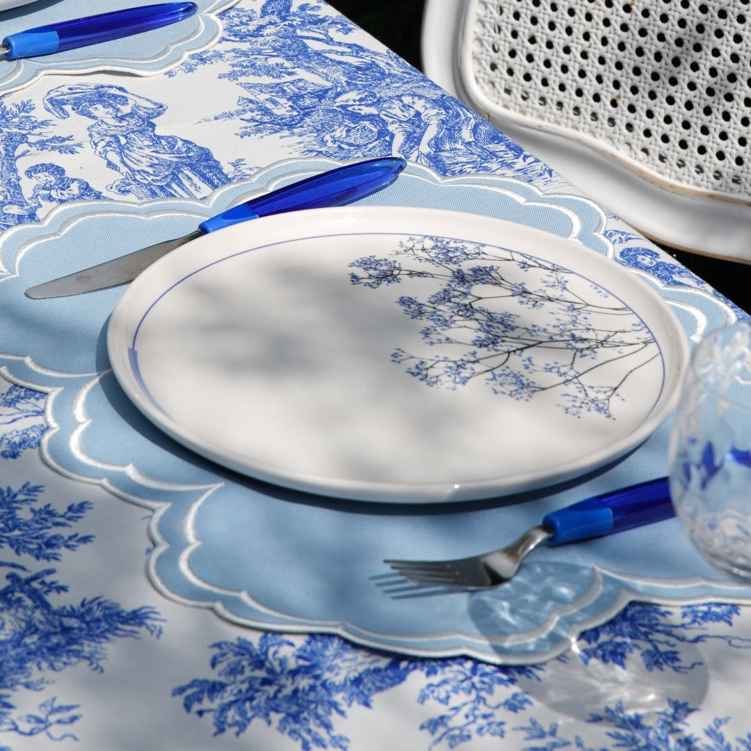 Dining table set with blue and white, cutlery, and a candle.