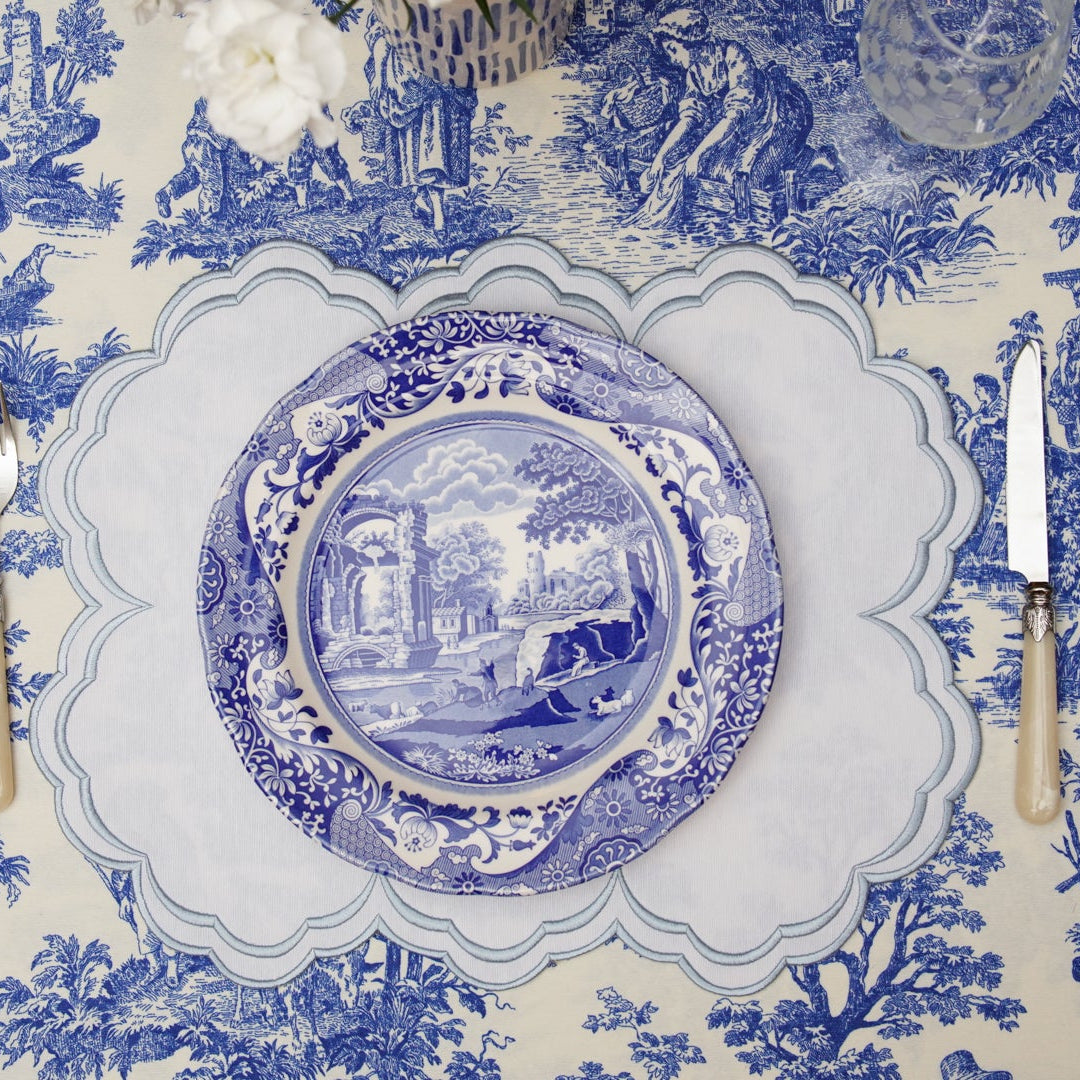 Table setting with blue and white patterned tablecloth, plates, and cutlery.