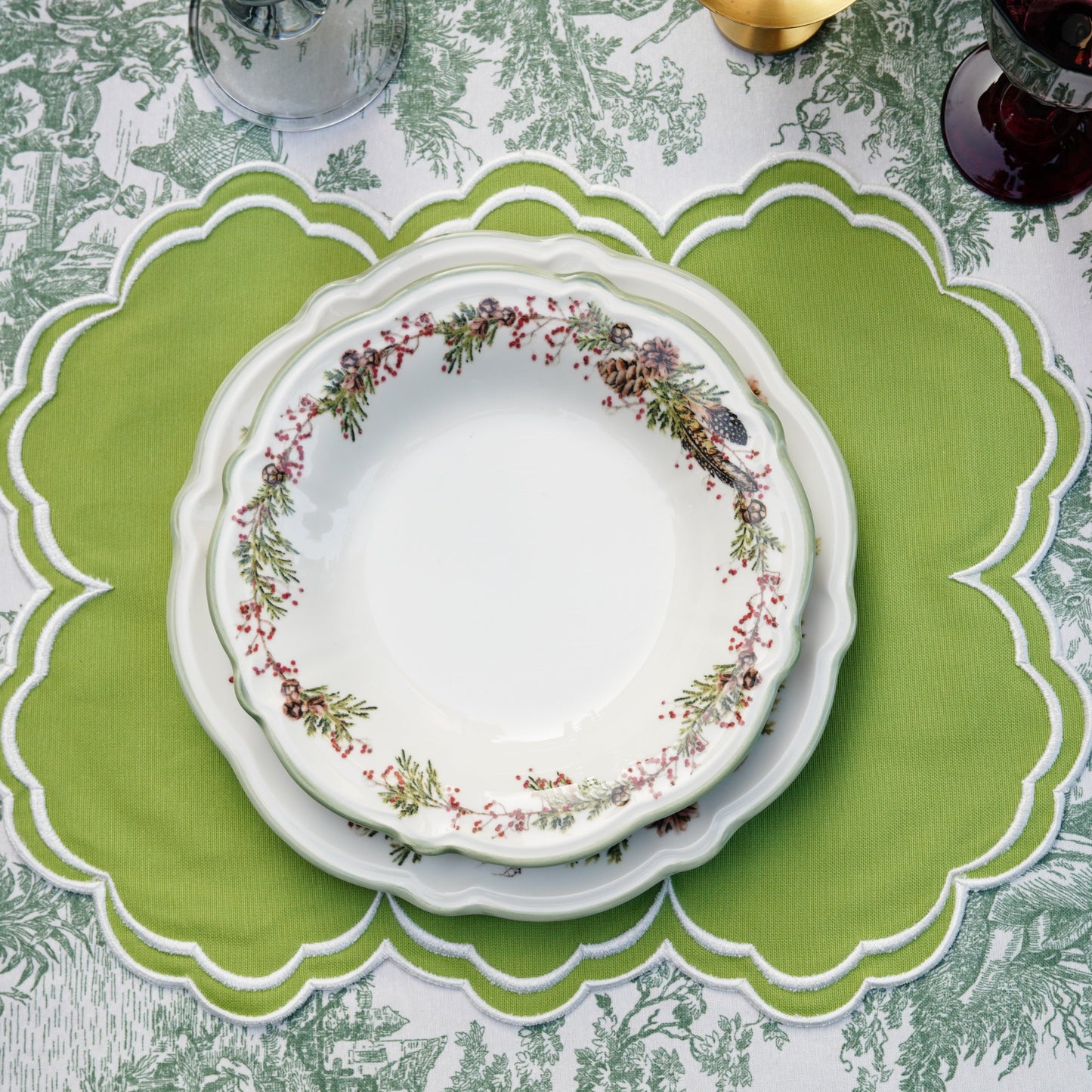 A green fabric placemat with white trim, displayed on a table with a plate and cutlery, part of a table setting.