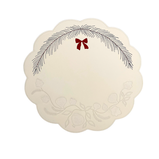 Round white faux leather placemat with a Christmas wreath and red bow design in the center.