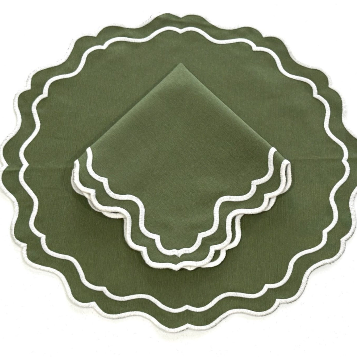A set of dark green placemats with a scalloped edge and white embroidery, displayed on a white background.