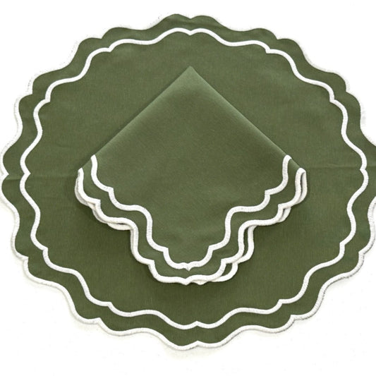A set of dark green placemats with a scalloped edge and white embroidery, displayed on a white background.
