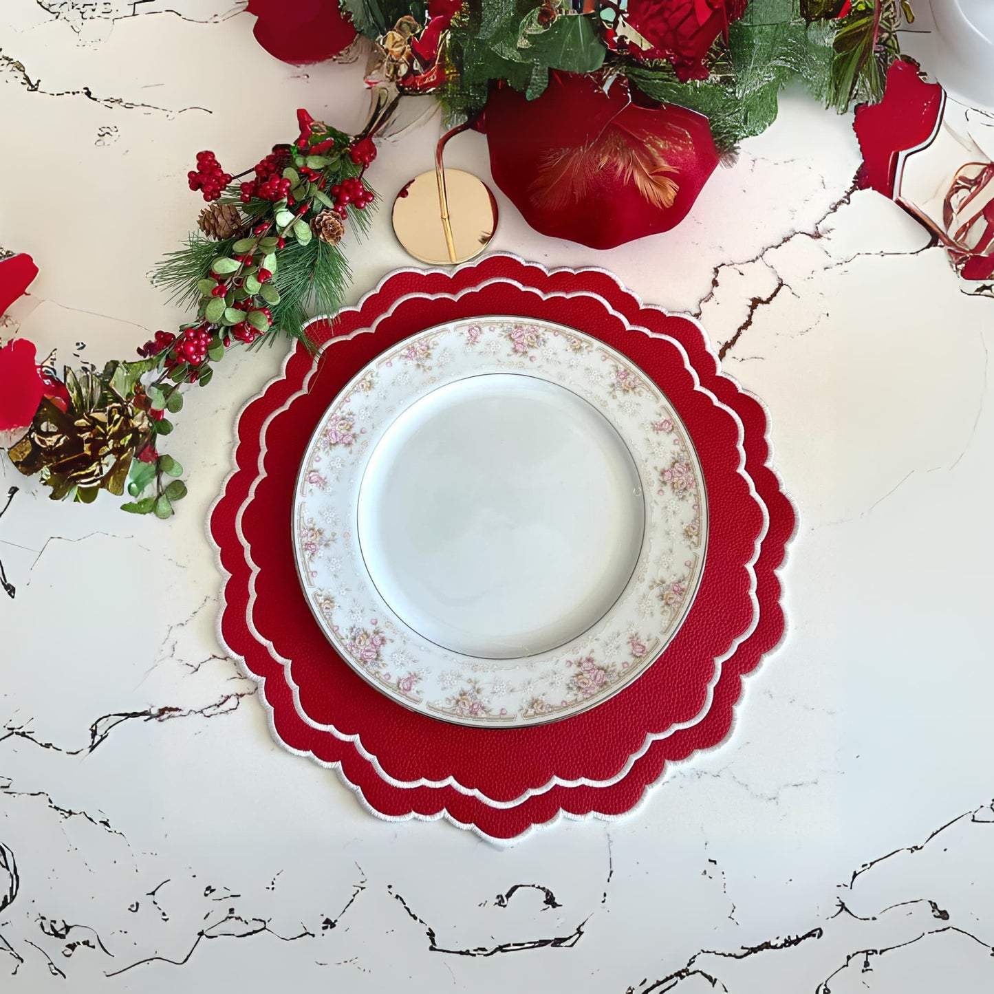 A red faux leather placemat with white floral embroidery, displayed on a table with decorative elements around it.
