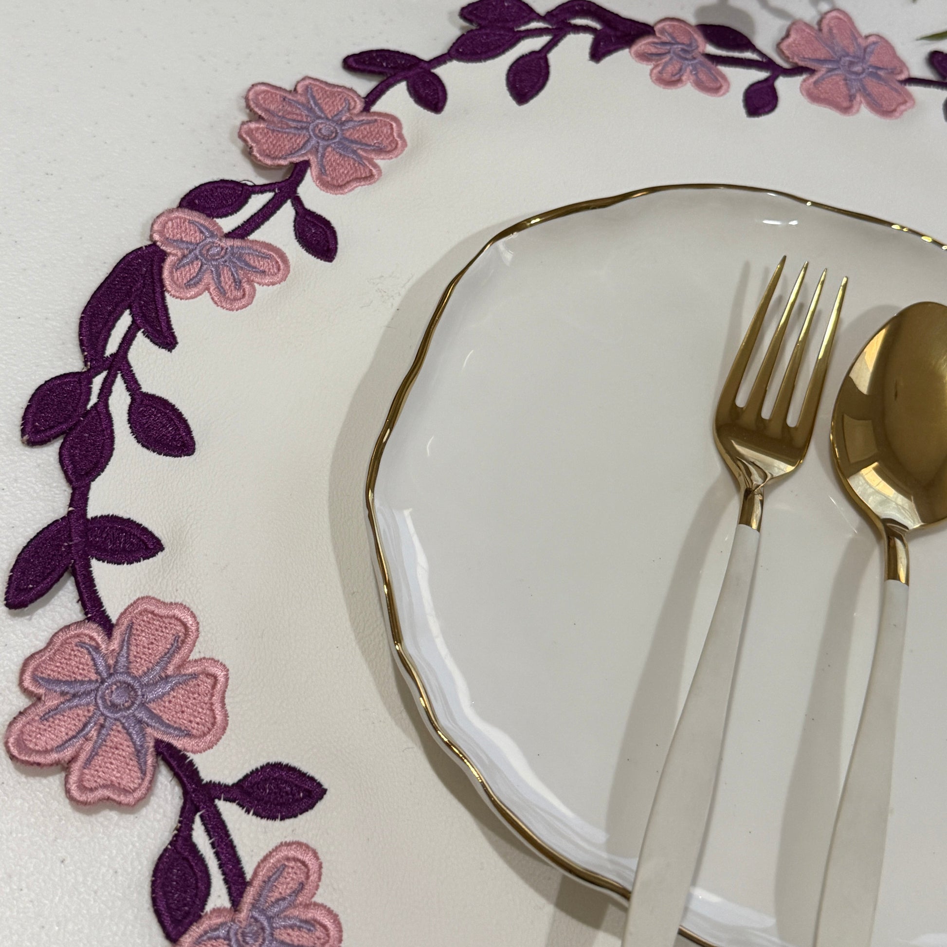 Decorative plate with floral design and cutlery on a white surface