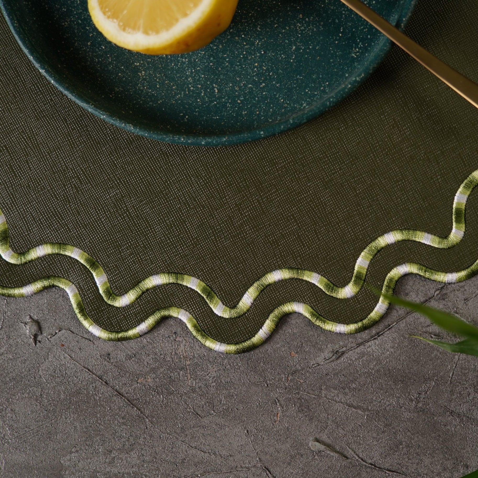 Green plate with a lemon wedge on a textured dark surface