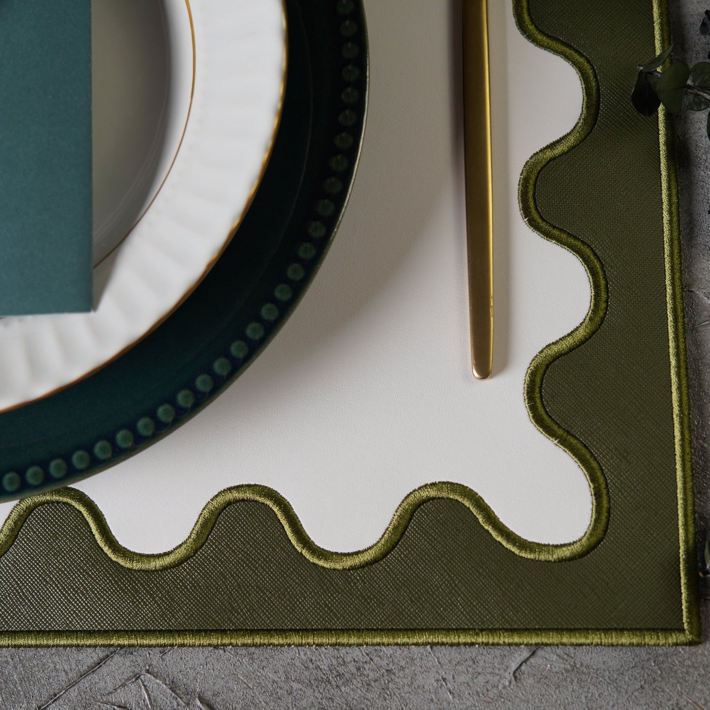 Close-up of a decorative green frame with wavy edge on a textured surface.
