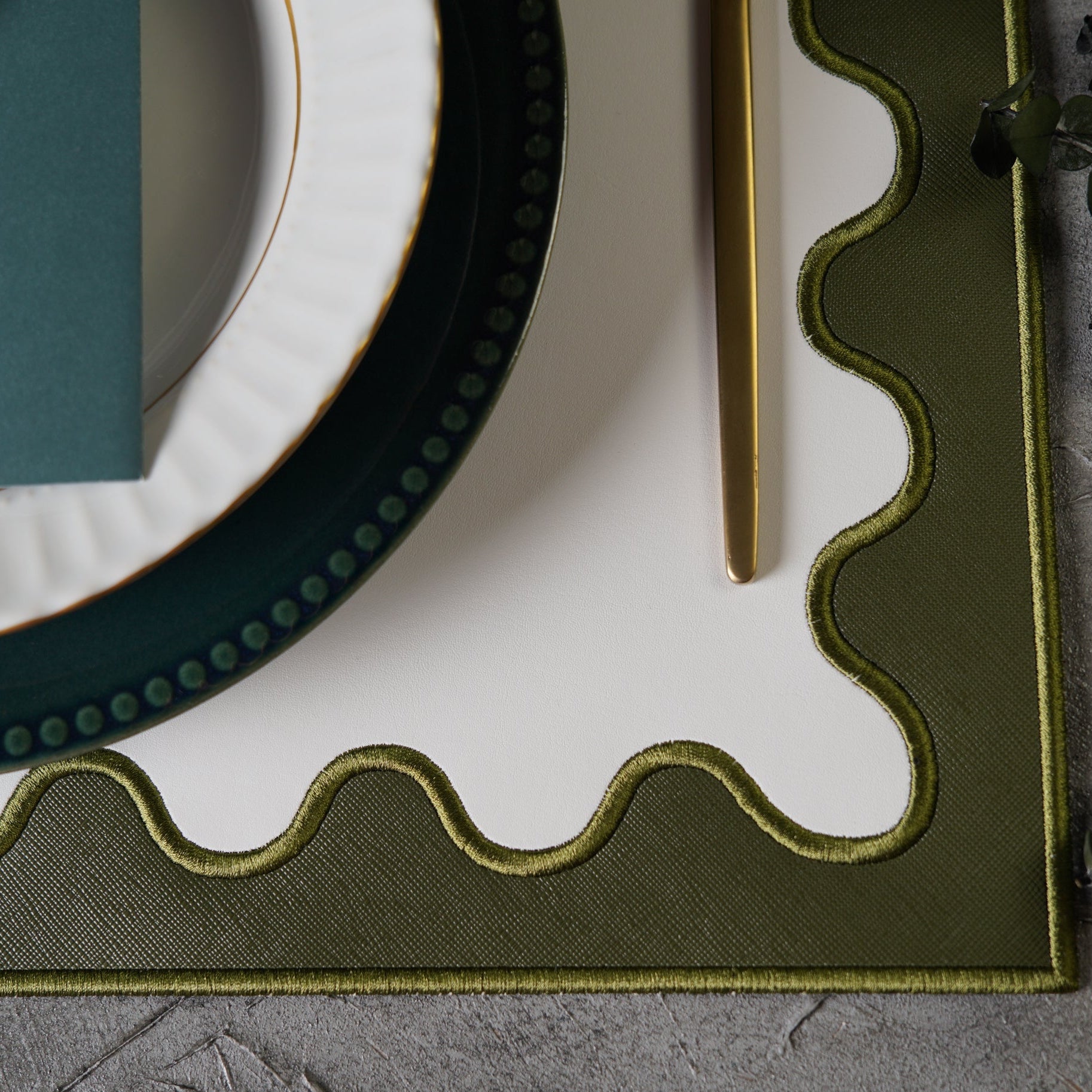 Close-up of a decorative green frame with wavy edge on a textured surface.