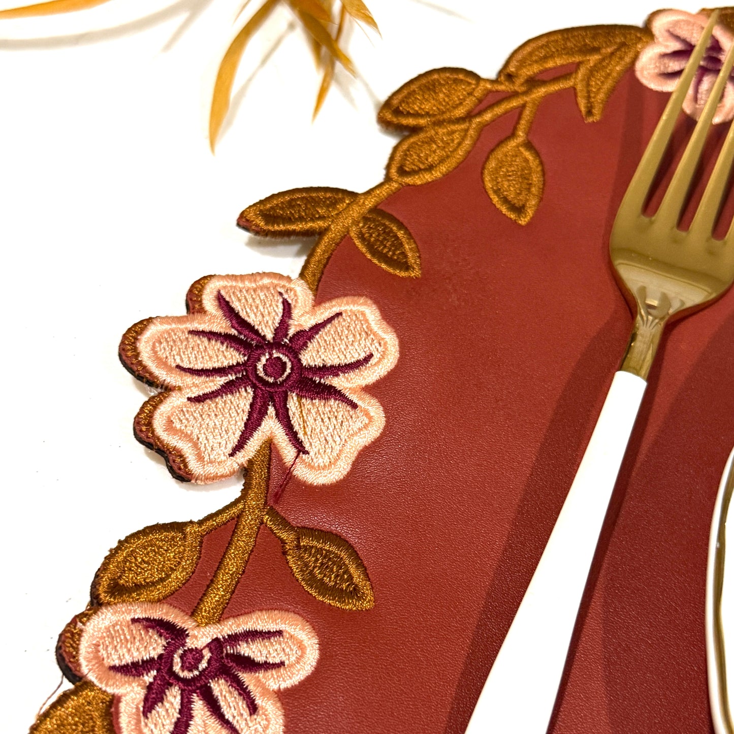Decorative floral-patterned placemat with a gold fork on a white background