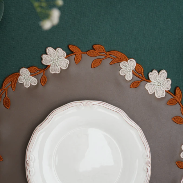 Decorative placemat with floral embroidery on a dark surface