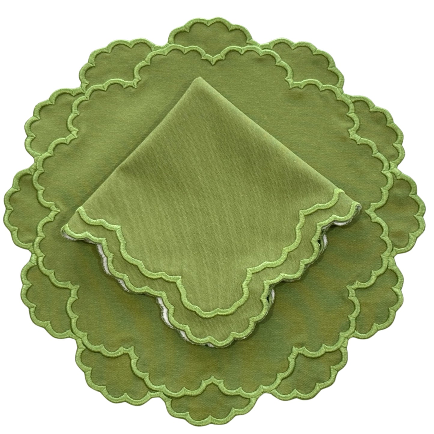 A set of green fabric placemats and napkins with scalloped edges.