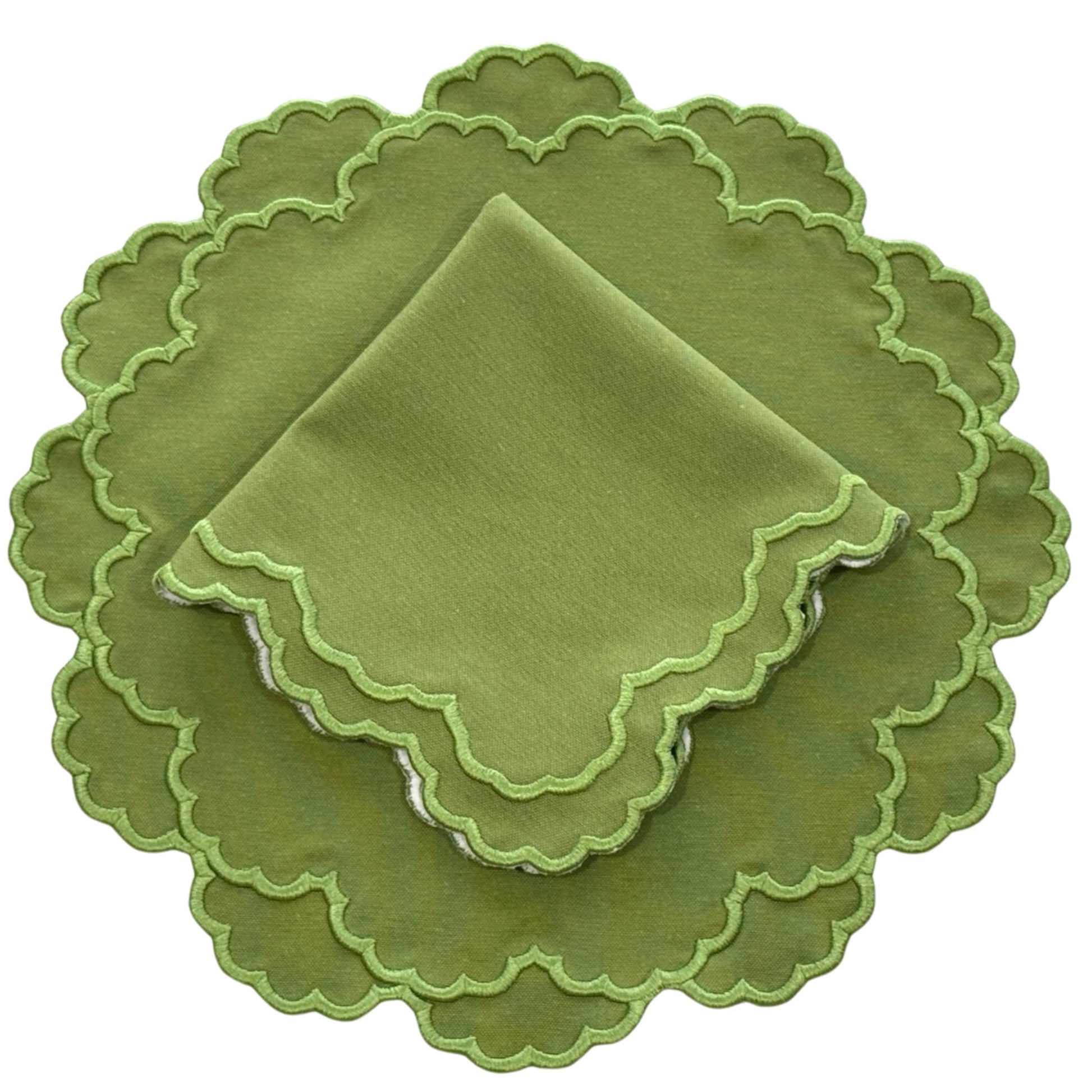A set of green fabric placemats and napkins with scalloped edges.