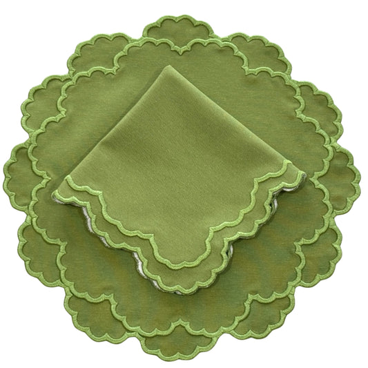 A set of green fabric placemats and napkins with scalloped edges.