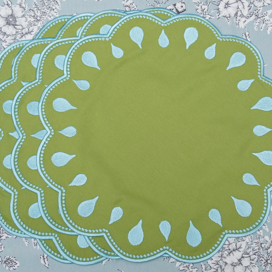 Set of green placemats with decorative edge on a floral-patterned background
