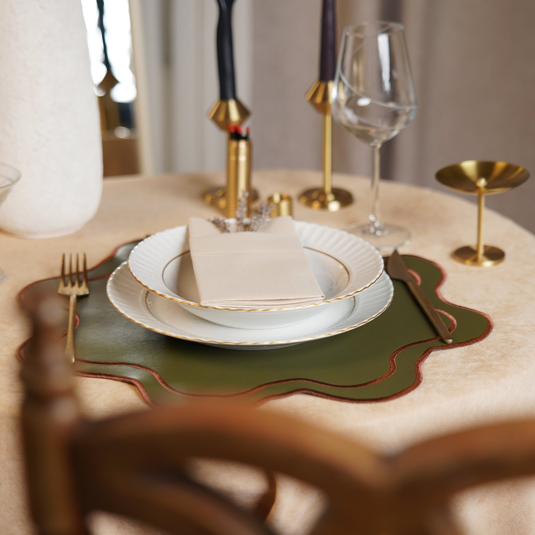 Dining table setting with plates, cutlery, and glasses on a green placemat.