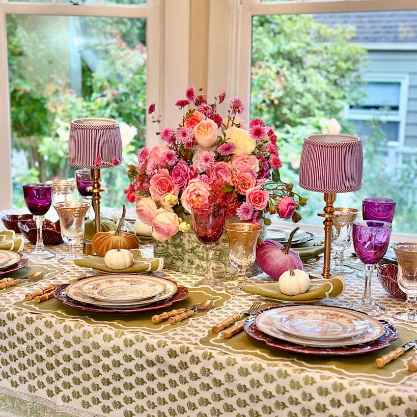 Decorative table setting with flowers, glasses, and cutlery in a bright room.