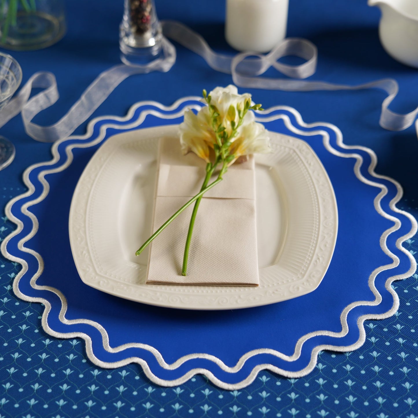 White plate with a flower arrangement on a blue tablecloth