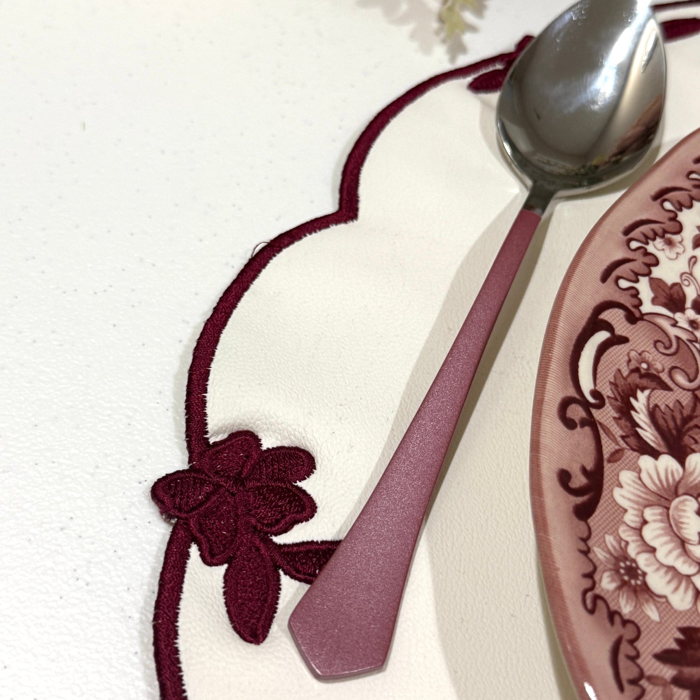 Spoon on a decorative plate with floral design on a white surface