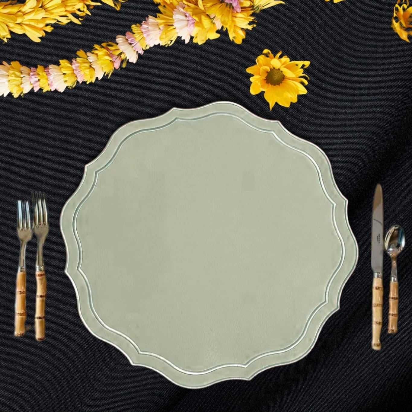 Green decorative plate on a black surface with yellow flowers and cutlery.