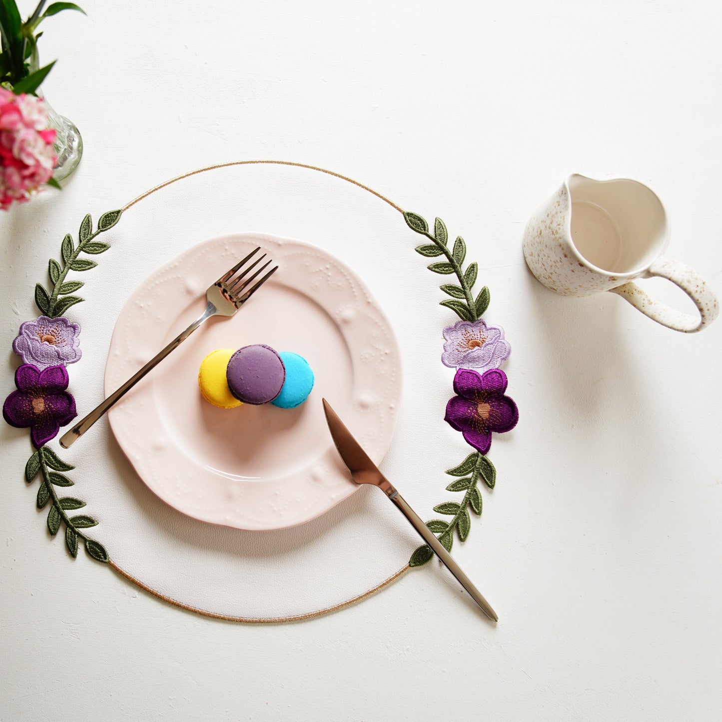 Easter-themed table setting with eggs, flowers, and cutlery on a white surface