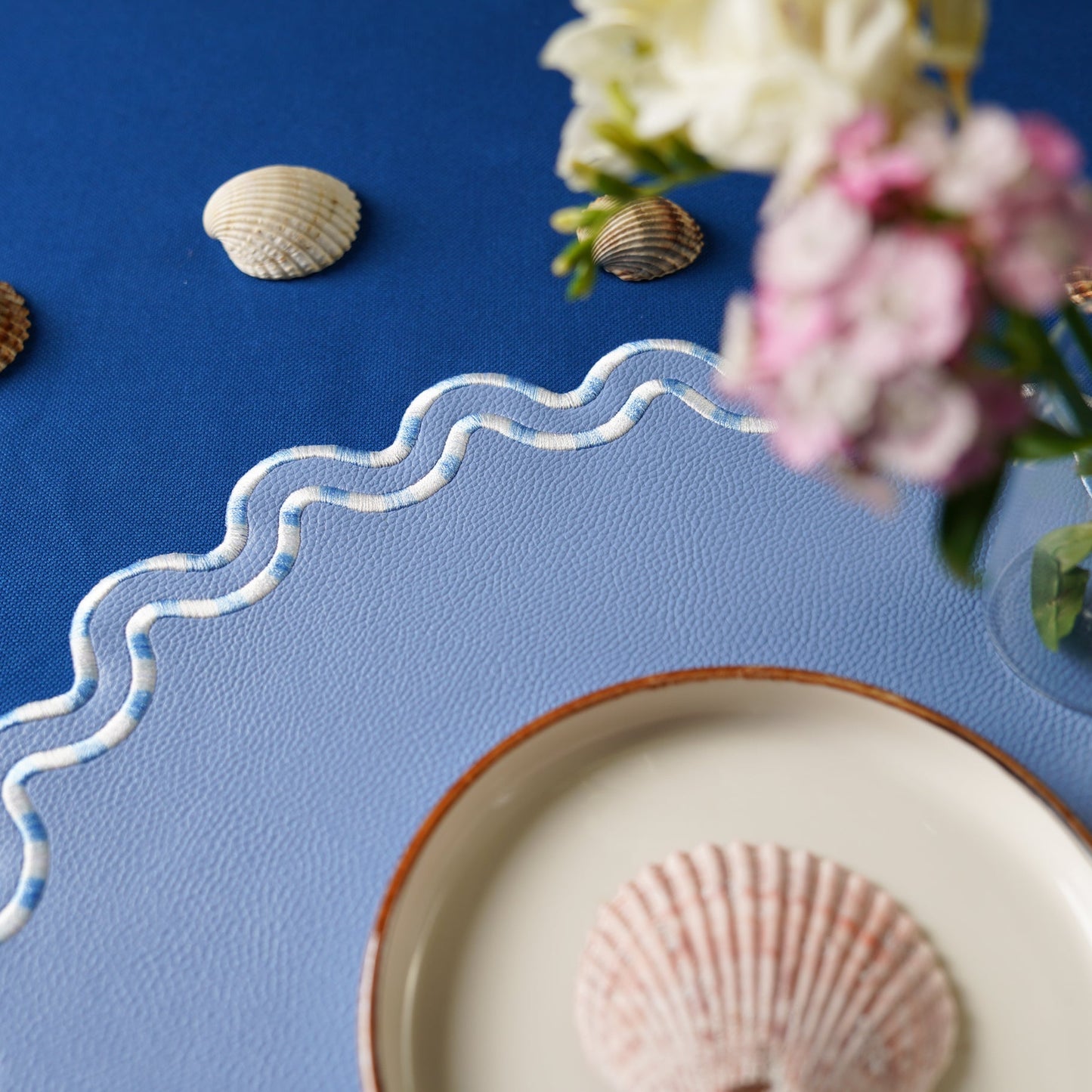 Blue placemat with decorative shell and floral design