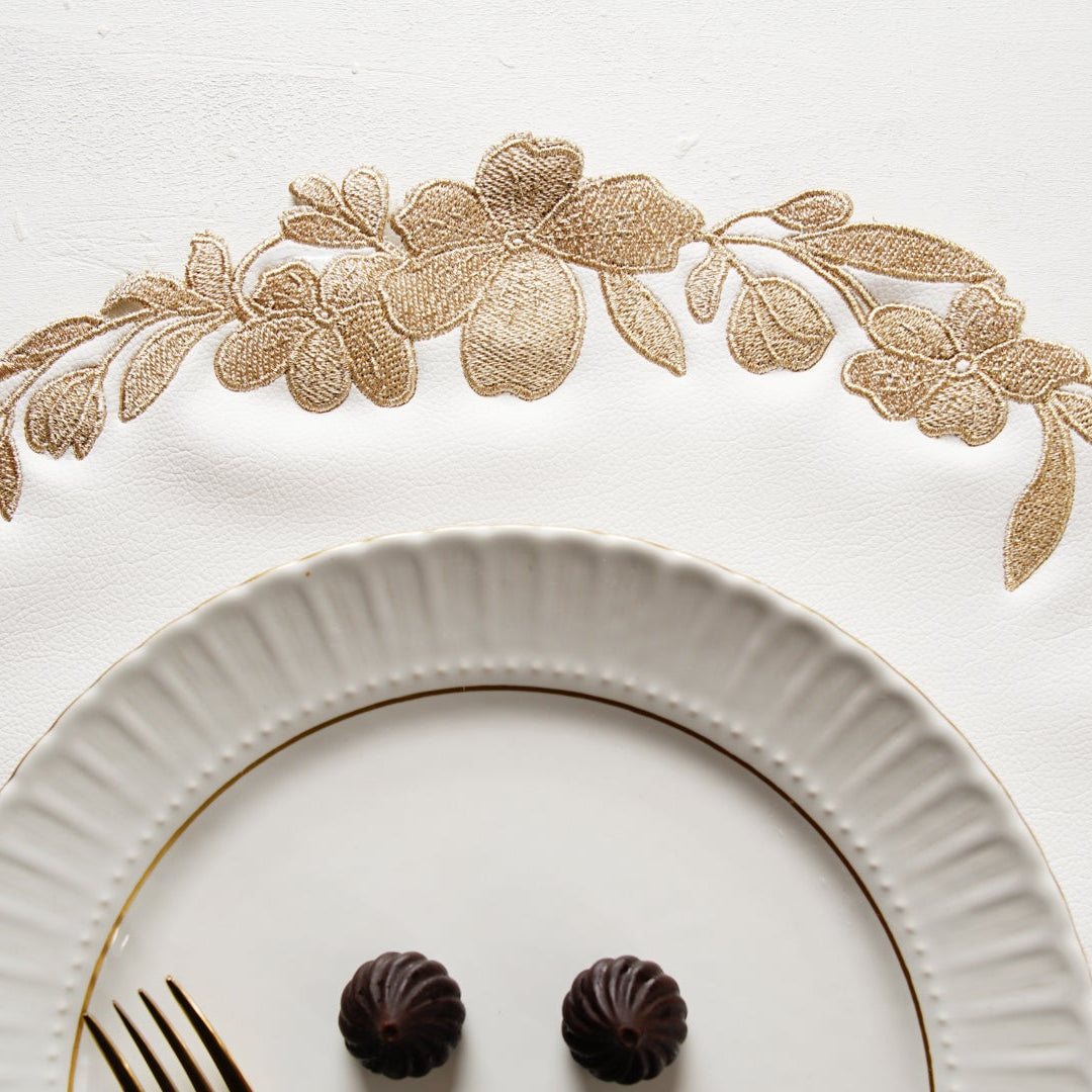 Decorative white plate with gold floral patterns and two chocolate truffles on a white background