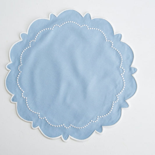 Light blue doily with scalloped edge on a light gray background