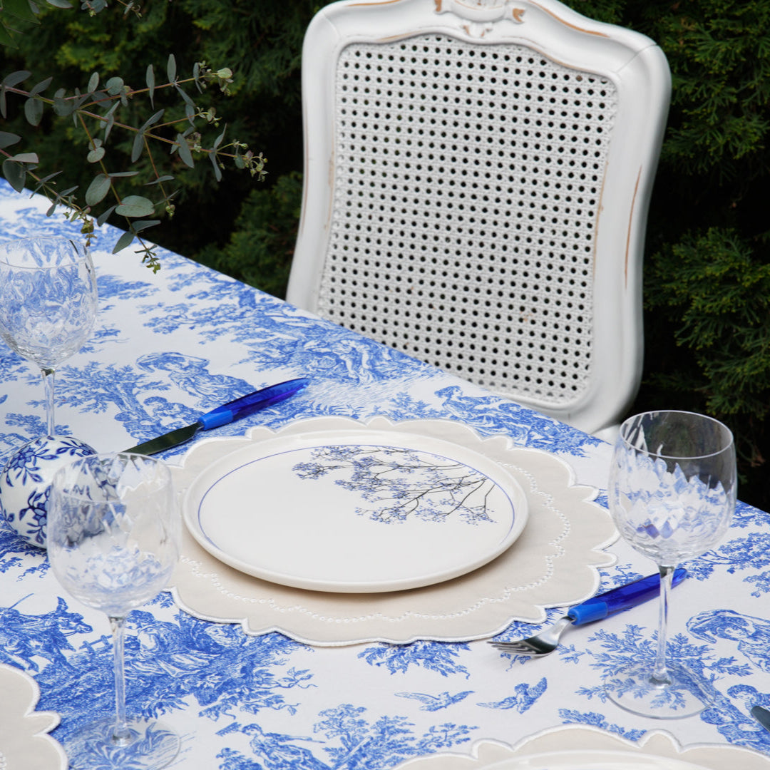 Dining table set with blue and white tablecloth, glasses, and cutlery.