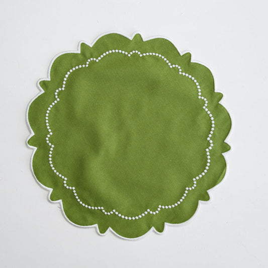 Green round placemat with white scalloped edge on a light gray background