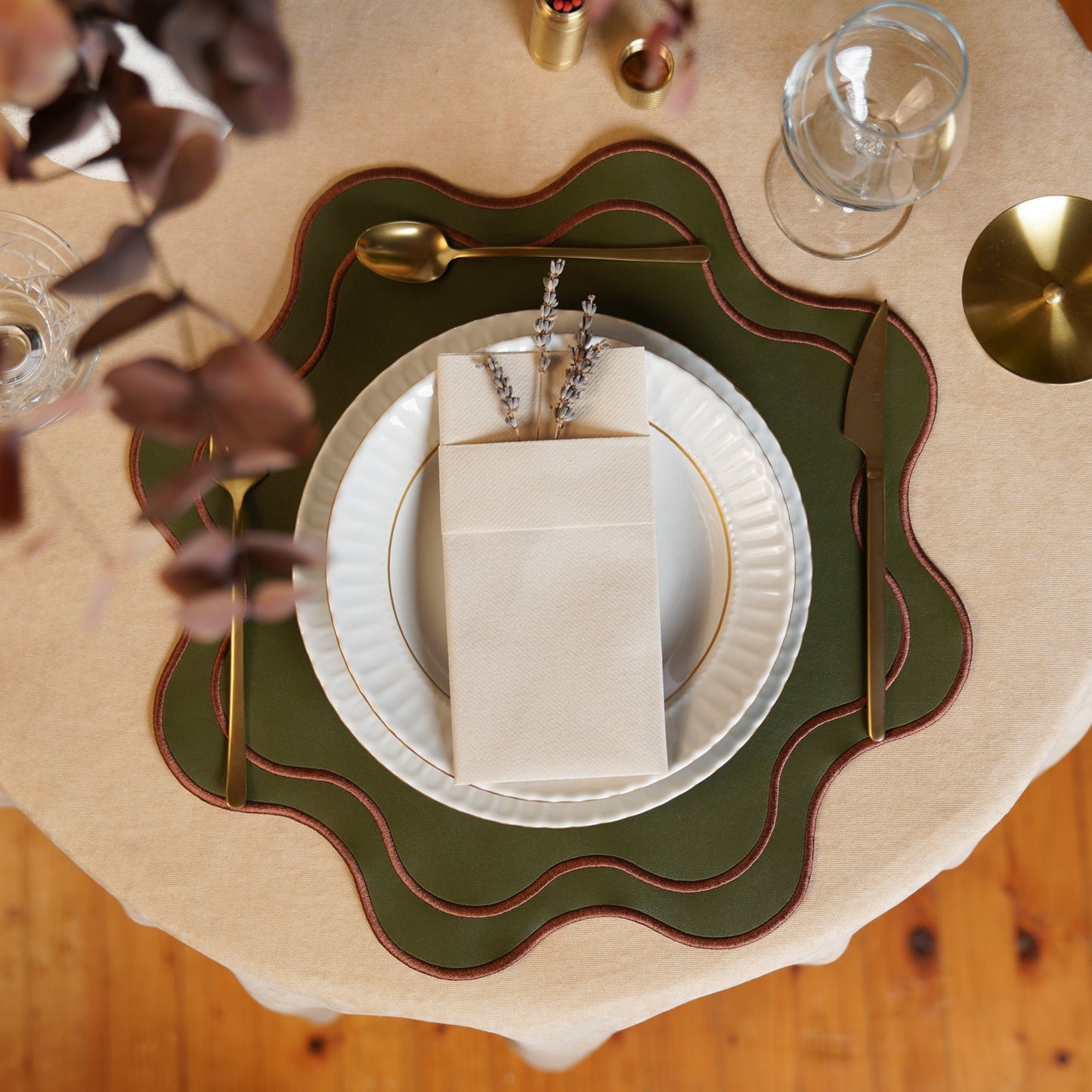 Table setting with a decorative green charger plate on a wooden table.