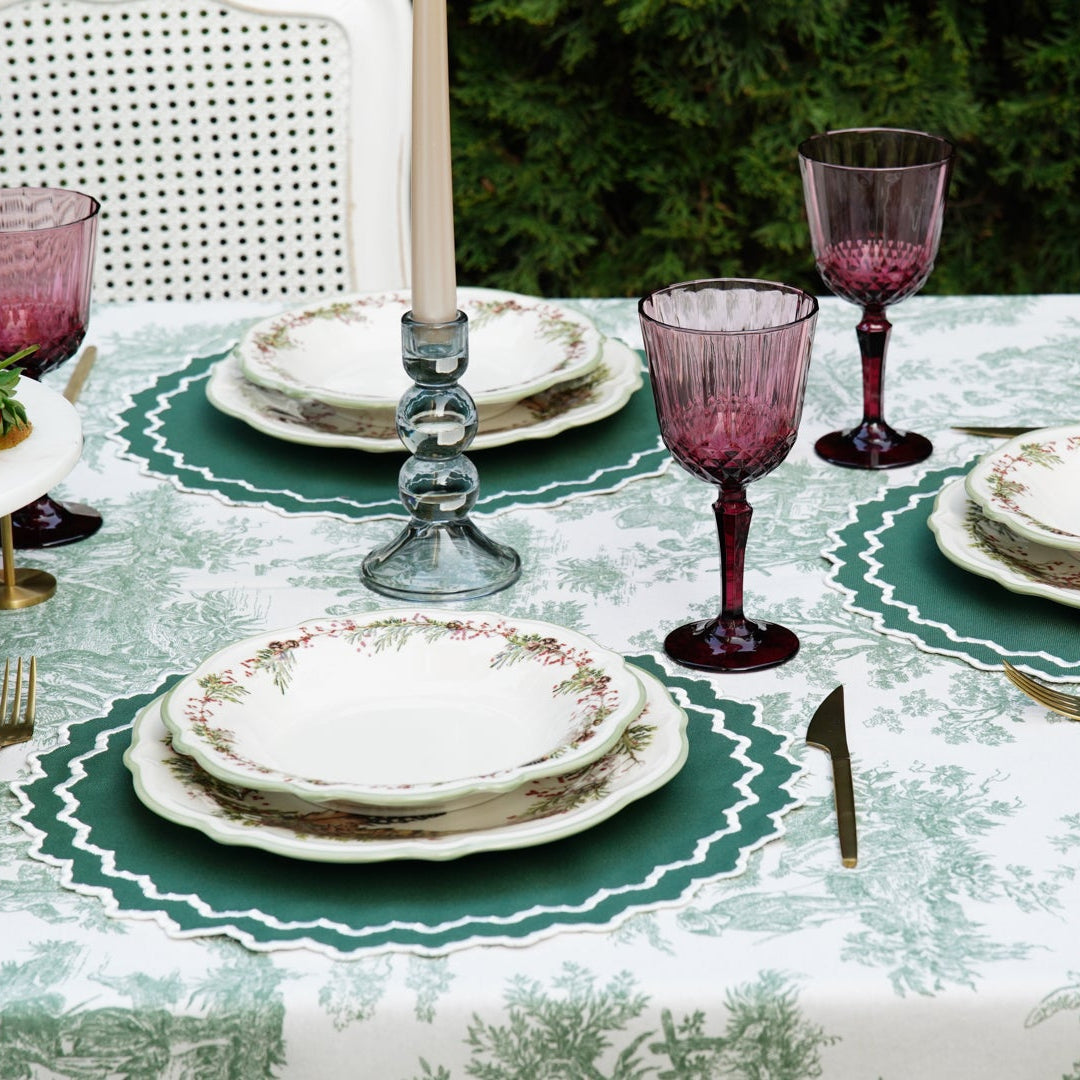 Elegant table setting with purple glasses and green placemats outdoors.