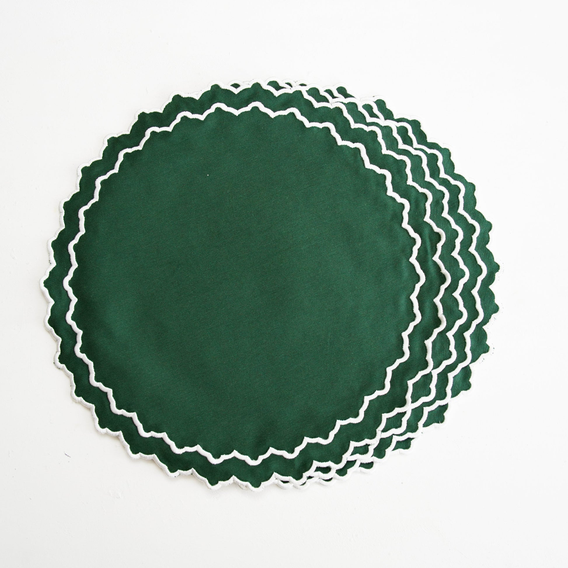 Set of green placemats with white scalloped edges on a white background