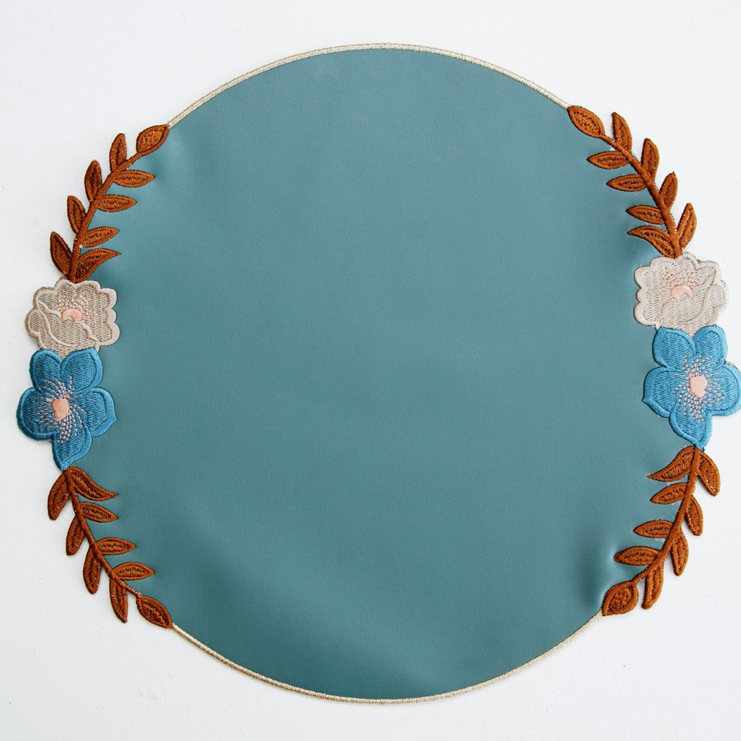 Teal plate with floral and leaf design on a white background