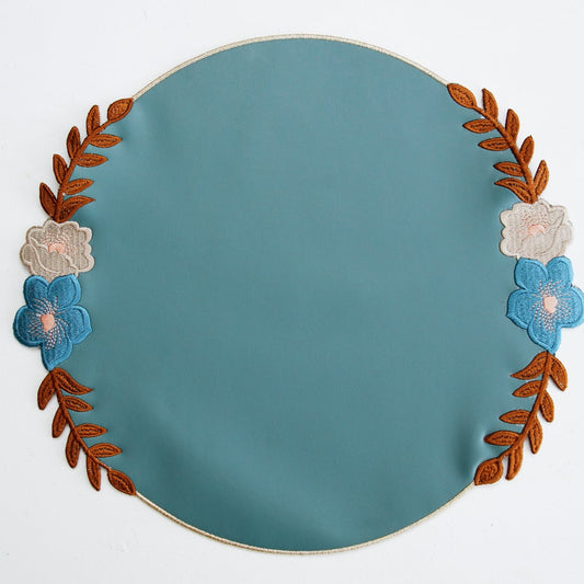 Teal plate with floral and leaf design on a white background