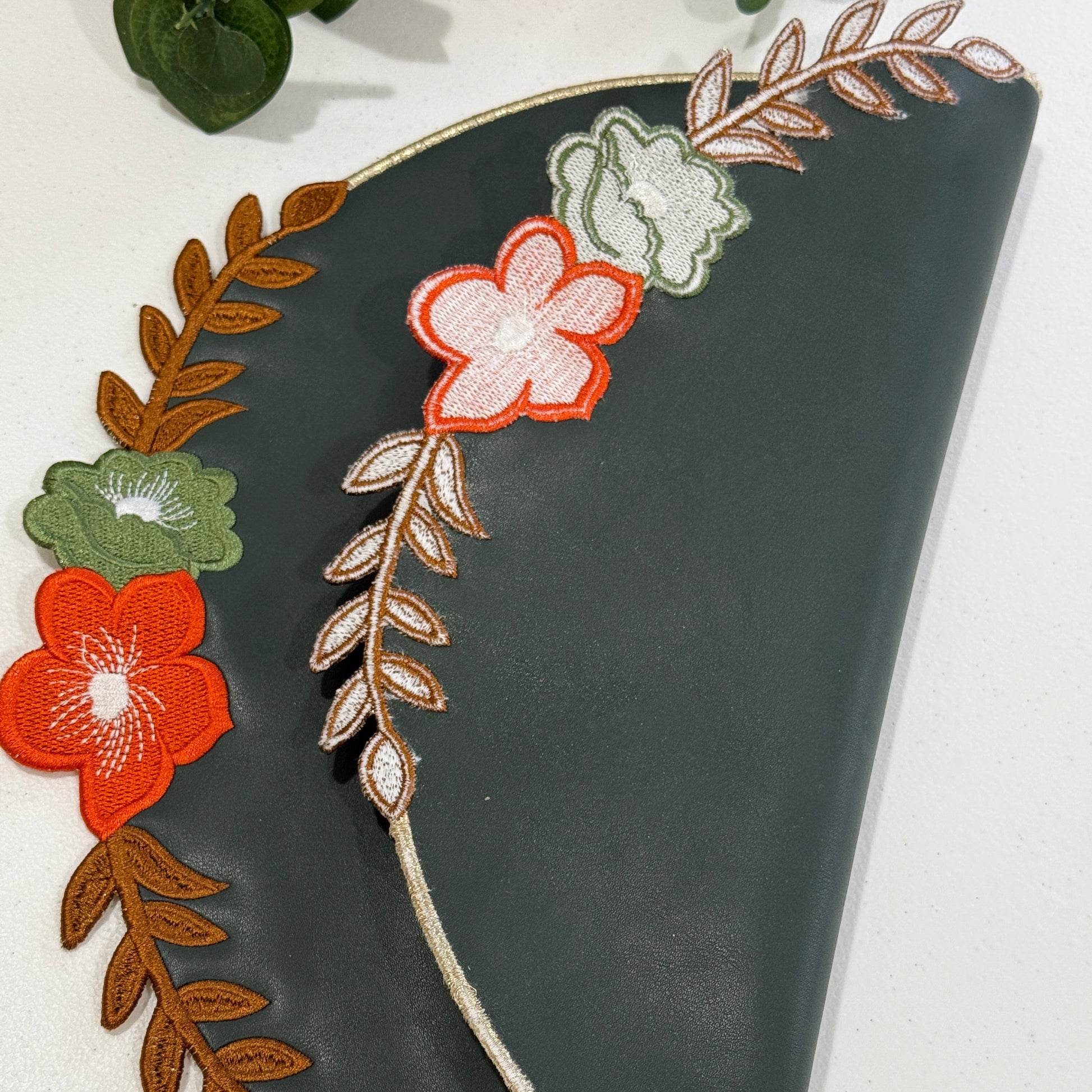 Black clutch with floral and leaf embroidery on a white background