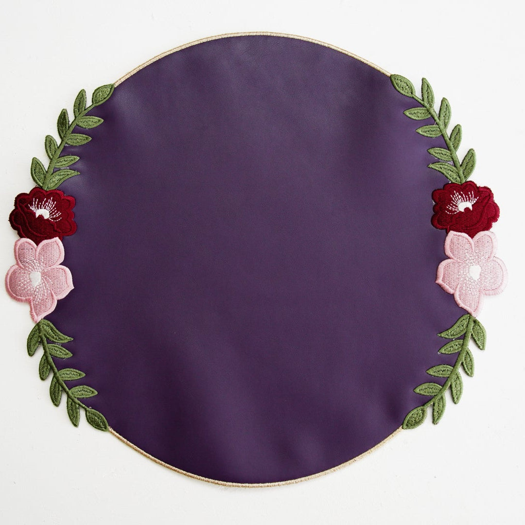 Round purple plate with floral decorations on a white background