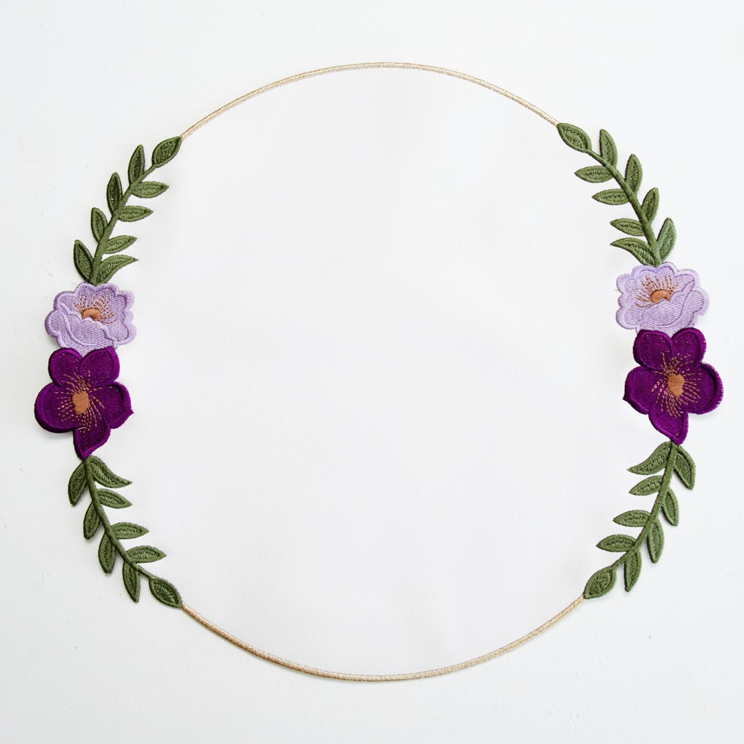Floral wreath with purple flowers and green leaves on a white background