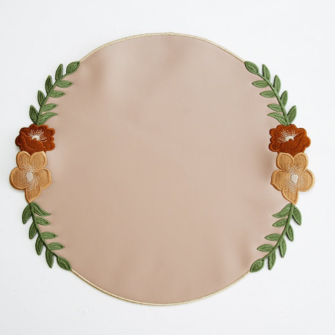 Round beige plate with floral and leaf decorations on a white background