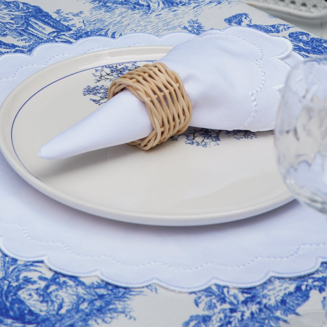 Elegant table setting with white plates, blue and white patterned tablecloth, and a glass.