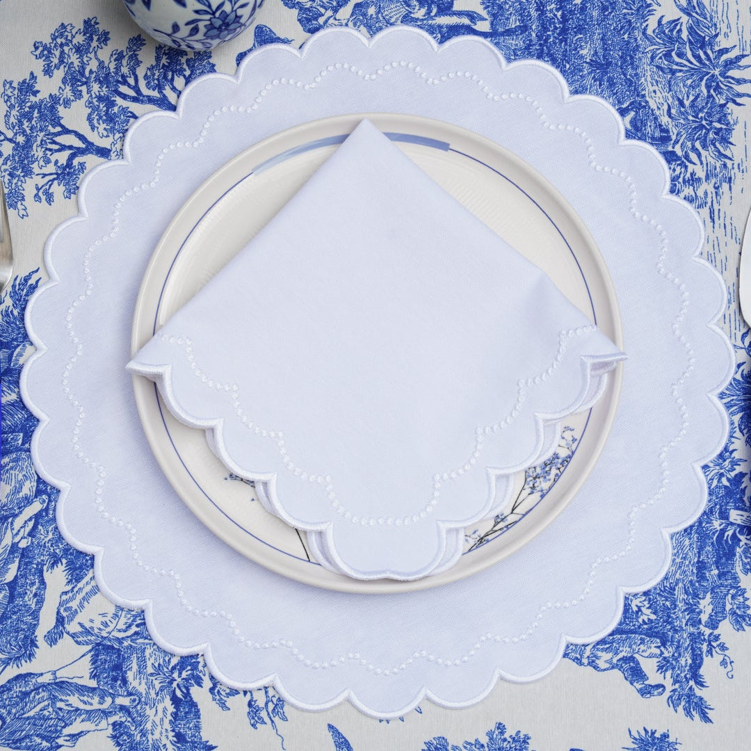 White plates and cutlery on a blue patterned tablecloth.