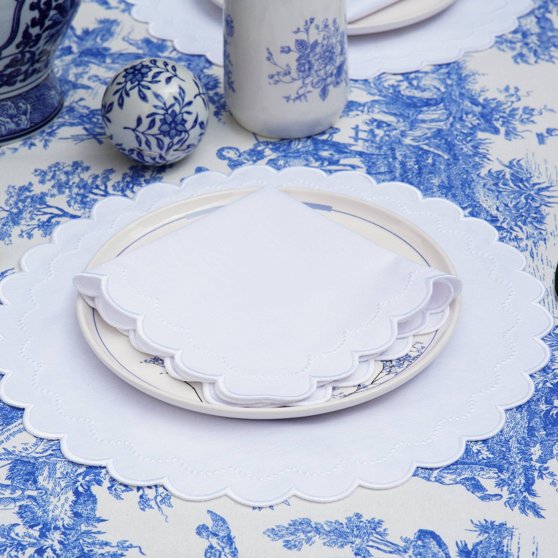 Table setting with blue and white on a patterned tablecloth.