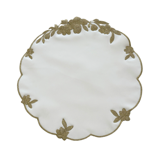 A round white faux leather placemat with gold floral embroidery around the edge.