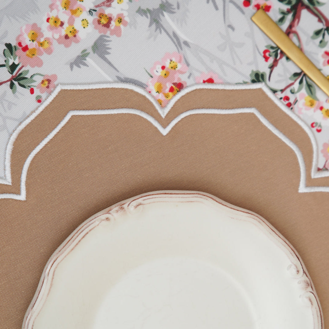 Decorative plates and cutlery on a floral tablecloth.