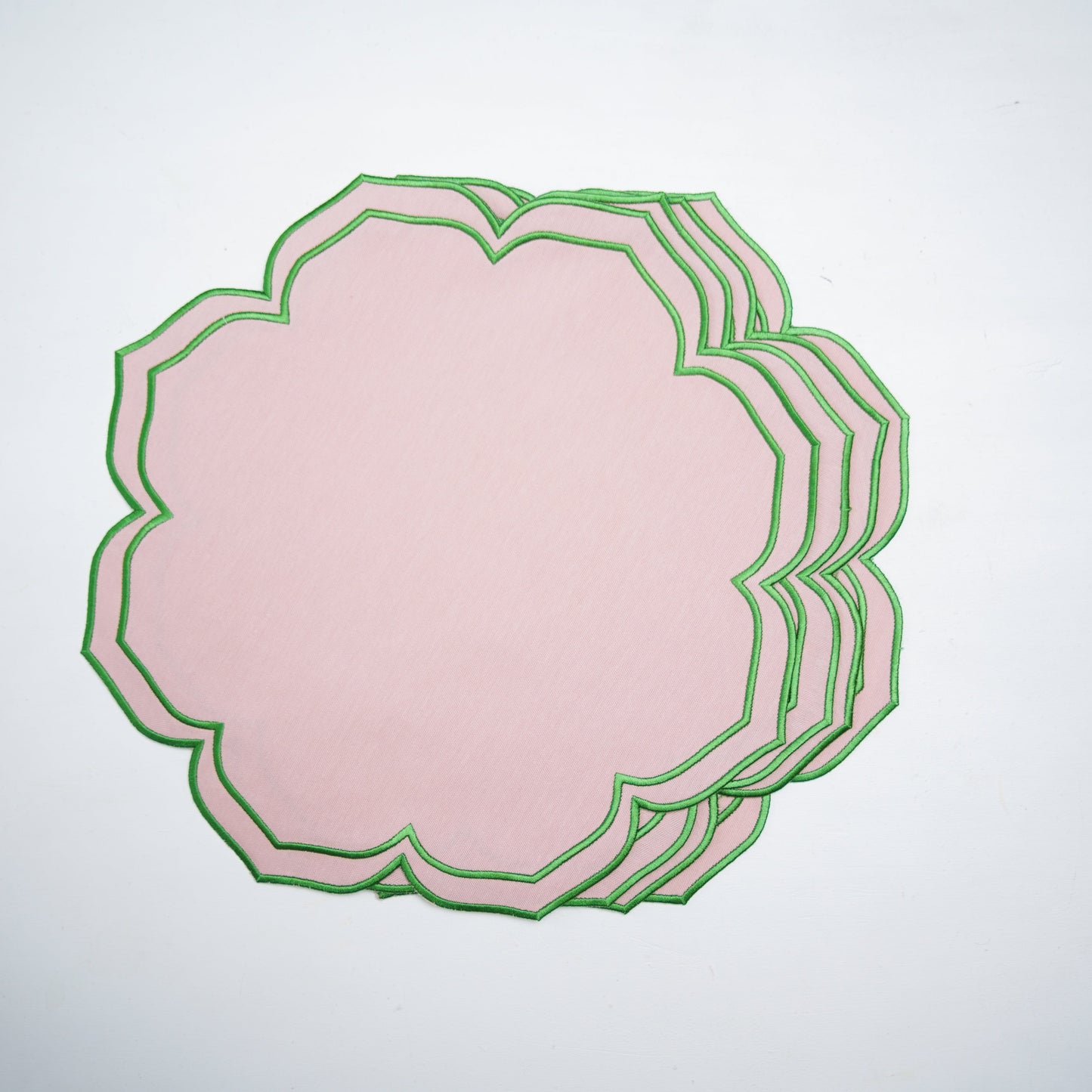 Stack of pink paper with green decorative border on a white background