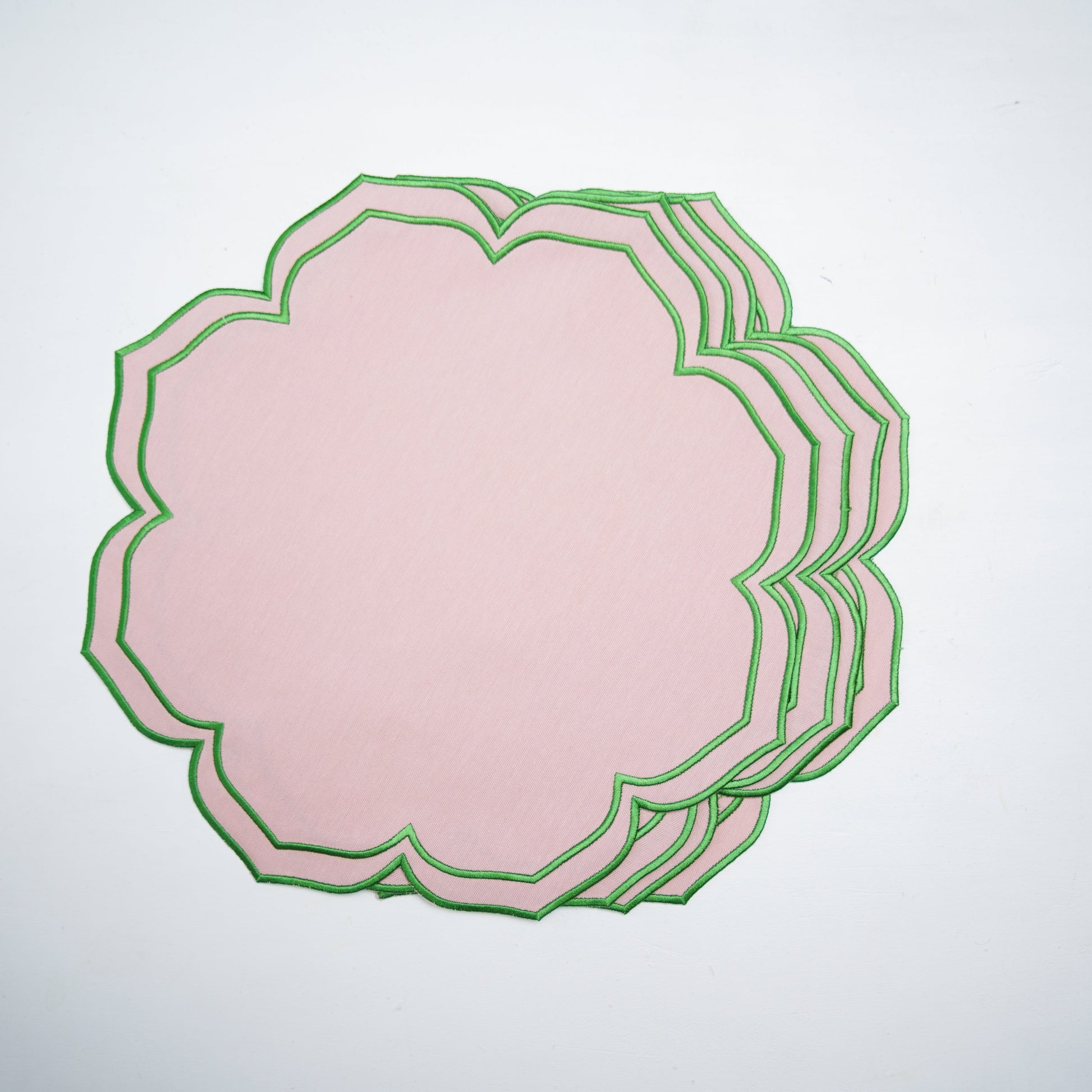 Stack of pink paper with green decorative border on a white background