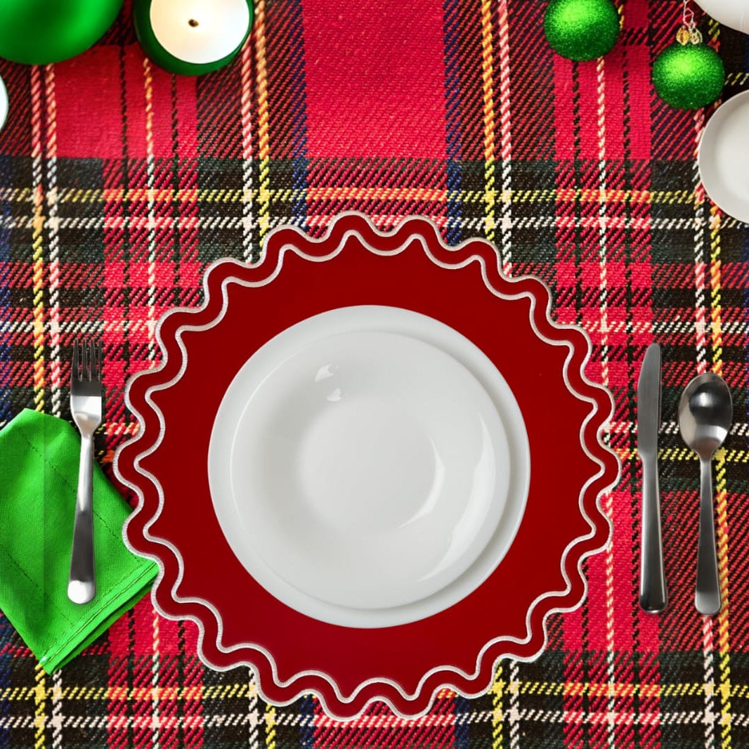 Plaid tablecloth with a red decorative plate, white plate, silverware, and green napkin.