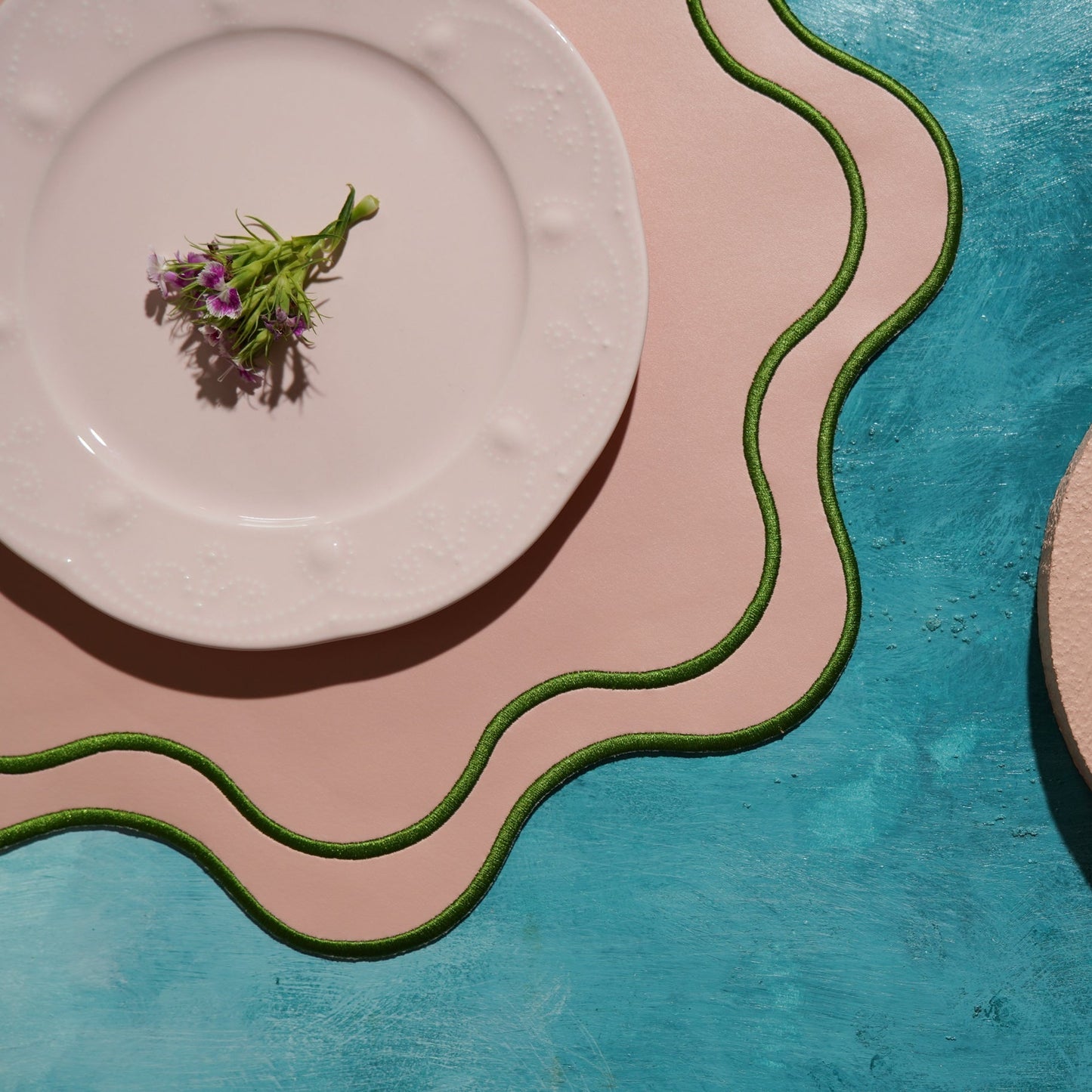 White plate with a small plant on a blue and pink textured surface