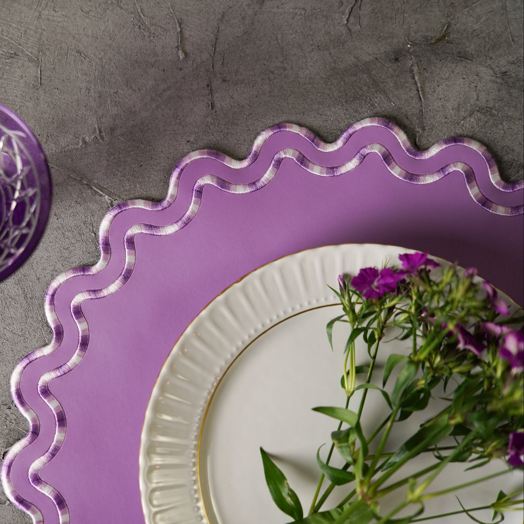 Purple decorative plate with scalloped edge on a gray surface