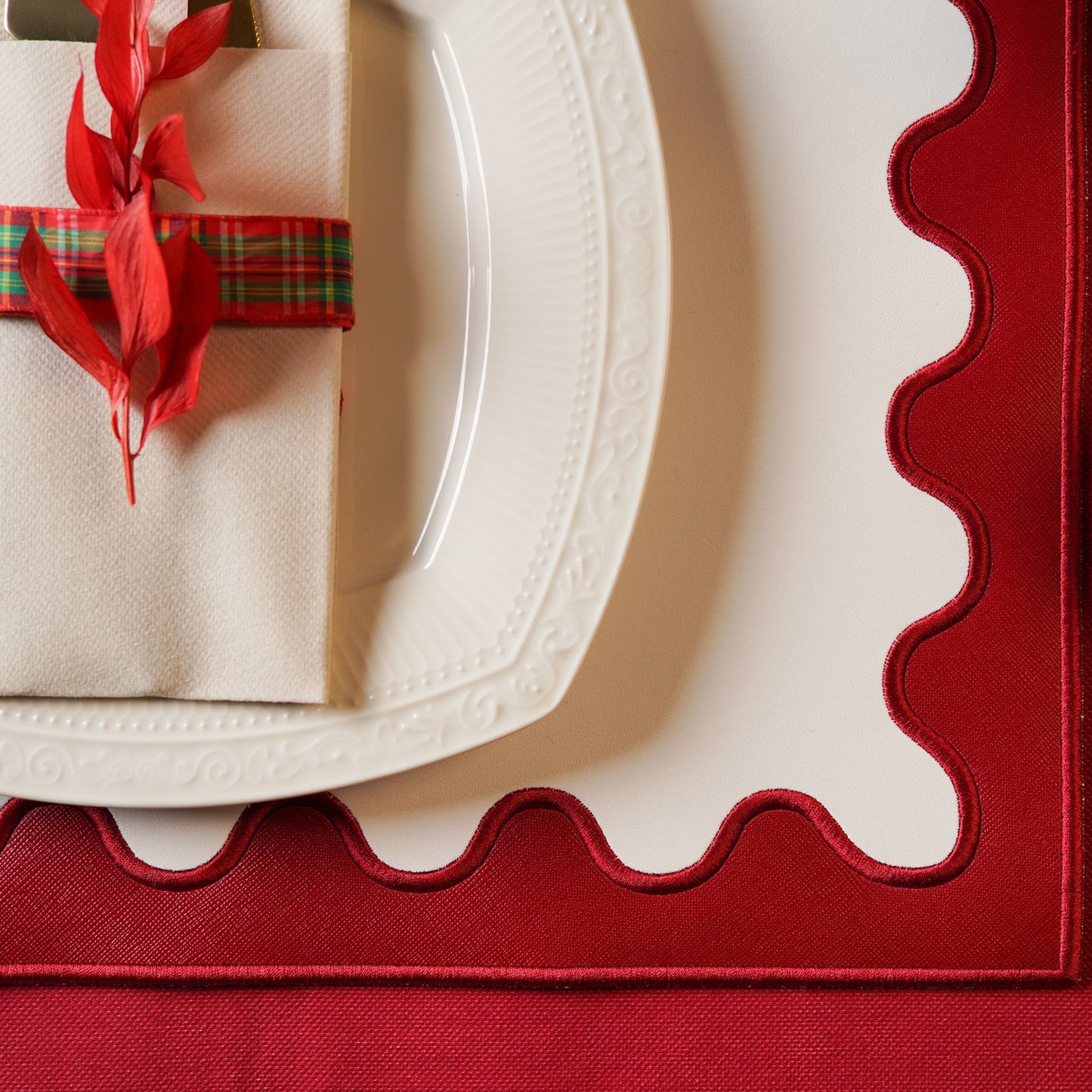 Close-up of a red placemat with a white plate and decorative napkin.