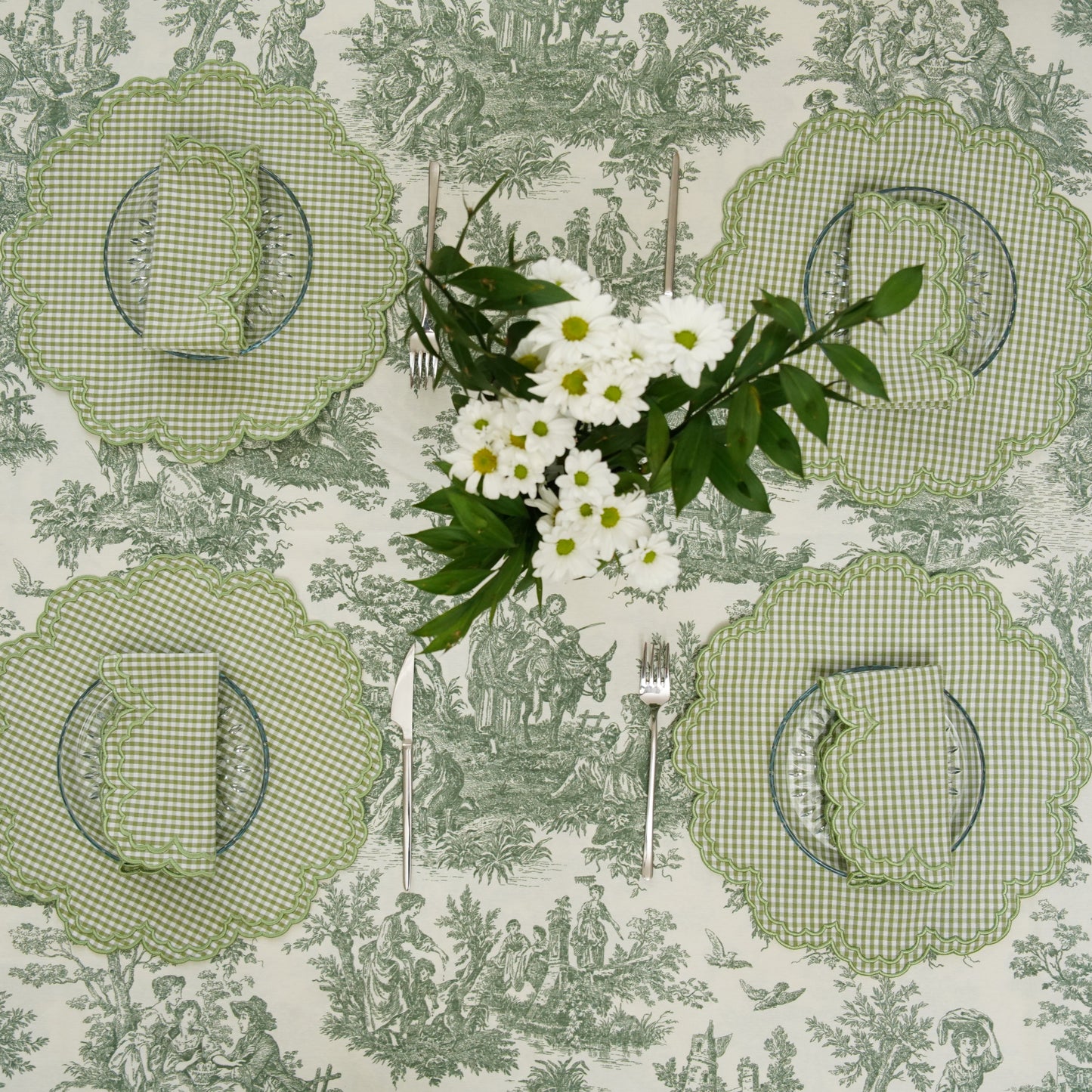Set of four green checkered placemats on a patterned tablecloth with a floral arrangement.