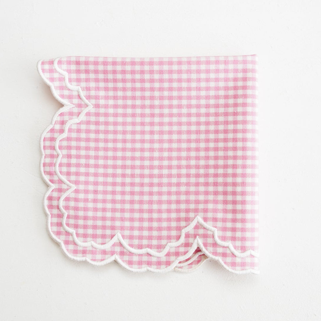 Pink gingham fabric with scalloped edge on a white background